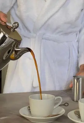 a person pouring coffee into a cup on a table at World Class Hotel - Istanbul Airport in Arnavutköy