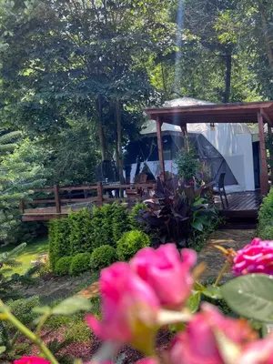 a garden with a wooden bench and pink flowers at ME-GA Glamping in Sapanca