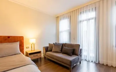 a bedroom with a bed and a couch and a window at Taksim 360 Luxe Apartment Prime Istanbul Location in Istanbul