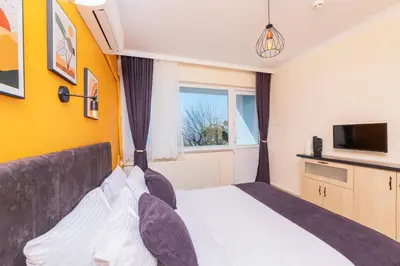 a bedroom with a bed and a tv and a window at KİRAZ BEACH OTEL in Erdek