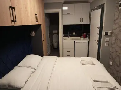 a bedroom with a bed with white cabinets and a kitchen at Middle Village in Istanbul