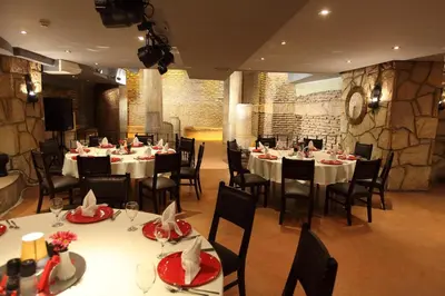 a restaurant with white tables and chairs and a stone wall at Antik Hotel Istanbul in Istanbul