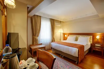 a hotel room with a large bed and a table at Hotel Sumengen in Istanbul