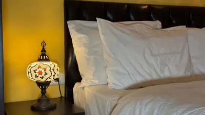 a bed with white pillows and a lamp on a table at Cosmopolitan Park Hotel in Istanbul