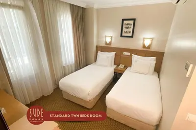 two beds in a hotel room with white sheets at Sude Konak in Istanbul