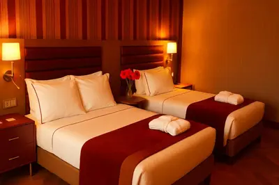 two beds in a hotel room with two roses at Taksim Gonen Hotel in Istanbul