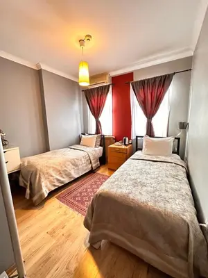 two beds in a room with red walls and wooden floors at Ahmet Efendi Evi in Istanbul