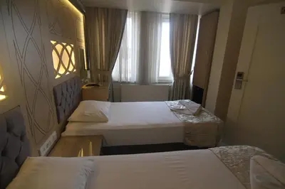 a hotel room with three beds and a window at Grand Liza Hotel in Istanbul