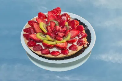 a cake with strawberries on a plate on a table at Hotel Daphne in Istanbul