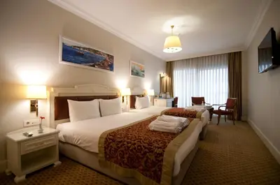 a hotel room with two beds and a desk at Taksim Metropark Hotel in Istanbul
