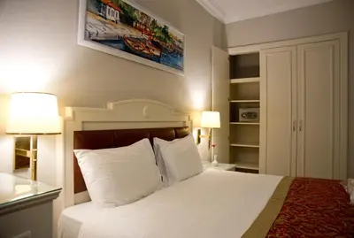 a bedroom with a bed with white sheets and two lamps at Taksim Metropark Hotel in Istanbul