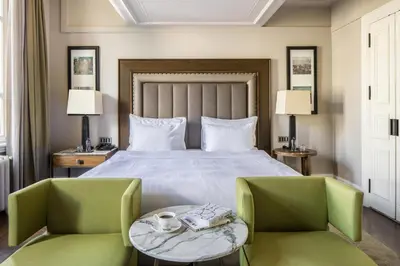 a bedroom with a bed and two green chairs at The Bank Hotel Istanbul, a Member of Design Hotels in Istanbul