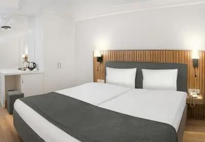a bedroom with a large white bed with a wooden headboard at Silvana Hotel in Istanbul