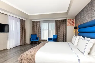 a hotel room with a large bed and blue chairs at Demiray Hotel Old City in Istanbul
