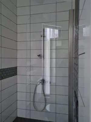 a shower in a white tiled bathroom at KD Apartments in Kartepe