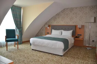 a bedroom with a large bed and a chair at Çınarpark Hotel in Korfez
