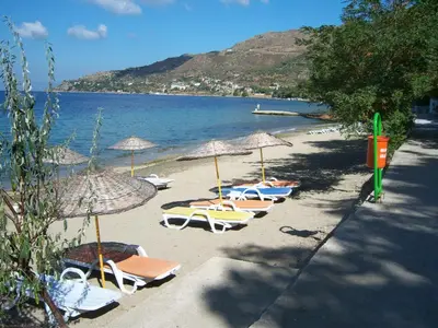 a group of chairs and umbrellas on a beach at Mola Hotel in Marmara Adasi