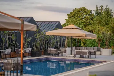 a pool with tables and chairs and an umbrella at Alya Kartepe Villa Hotel in Kocaeli