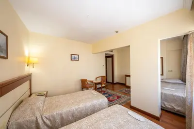a hotel room with two beds and a chair at Hotel Erdal in Istanbul