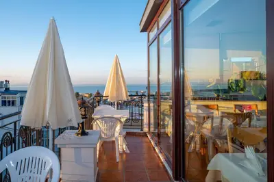 a balcony with tables and umbrellas and the ocean at Hotel Erdal in Istanbul