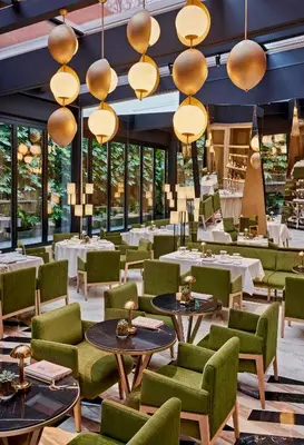 a restaurant with green chairs and tables and windows at Vakko Hotel and Residence in Istanbul