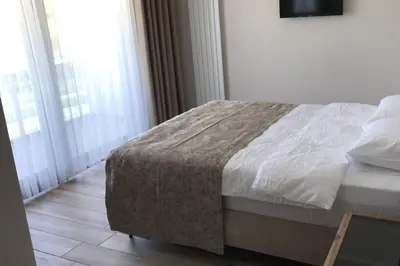 a bedroom with a bed with white sheets and windows at ANTİGONİA BUTİK OTEL in İznik