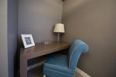 a room with a desk with a blue chair and a lamp at Semsan Hotel in Istanbul