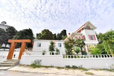 a white house with a fence and trees at Noya Köşk Otel in Adalar
