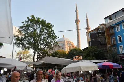 a group of people walking around a market with a mosque in the background at Çırağan's Omnia Hotel in Istanbul