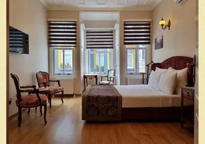 a bedroom with a bed and chairs and windows at Çırağan's Omnia Hotel in Istanbul