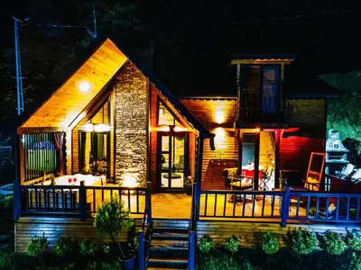 a small wooden house with a deck at night at LakeviewhouseSapanca in Sapanca
