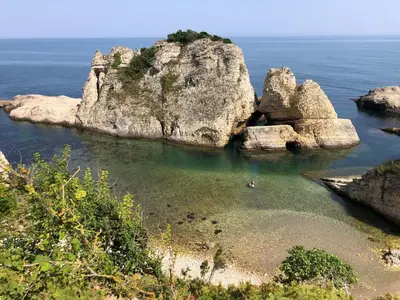 a person swimming in the water near a large rock formation at DEFNE OTEL in Sile