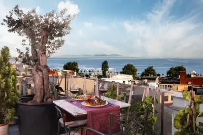 a table with food and wine glasses and a tree on a balcony at Skalion Hotel in Istanbul