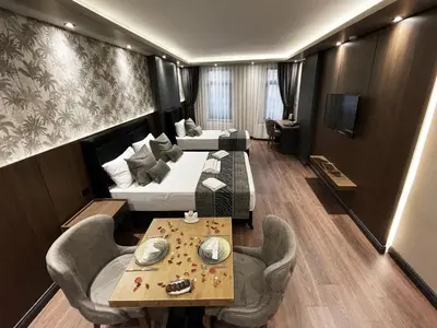 a hotel room with two beds and a table and chairs at GRAND ÜSKÜDAR OTEL in Istanbul