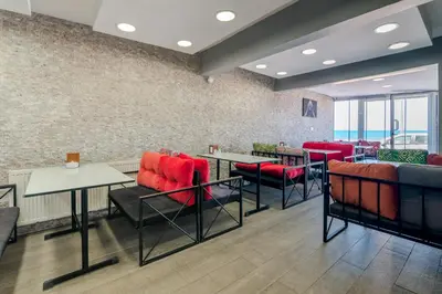 a restaurant with red chairs and tables and windows at Airport Black Sea Hotel & Restaurant in Arnavutköy