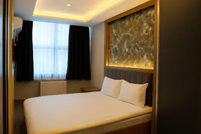 a bedroom with a bed with white sheets and a window at CALENBERG HOTEL in Istanbul