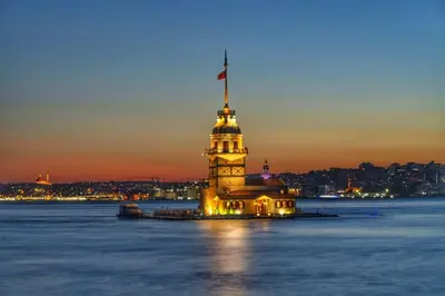 a building with a clock tower in the water at night at White Suites Hotel İstanbul in Istanbul