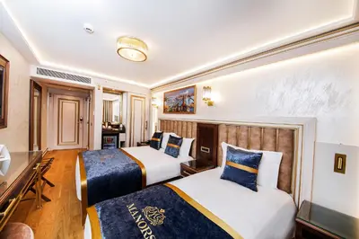 a hotel room with two beds and a desk at MANORS HOTEL in Istanbul
