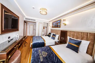 a hotel room with two beds and a flat screen tv at MANORS HOTEL in Istanbul