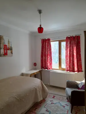 a bedroom with a bed and a window with red curtains at Turkish Mountain Retreat in Saadet