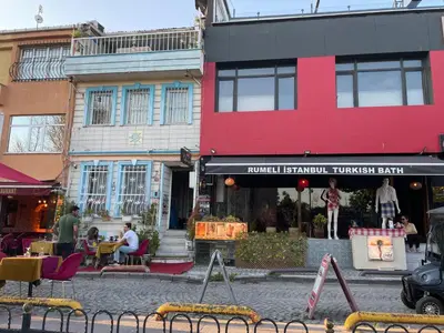 a street with a pink building and people sitting outside at antik sofia hotel in Istanbul
