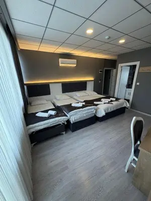 a room with three beds and a chair in it at ÖZTÜRKS HOTEL in Istanbul