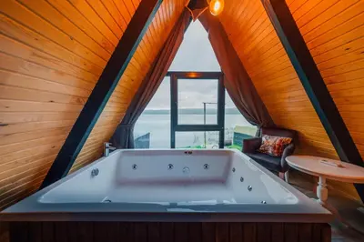 a bath tub in a room with a large window at Kurtköy Park Bungalov Evleri in Sakarya