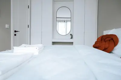 a white bedroom with a bed and a mirror at Bolahenk Suites in Istanbul