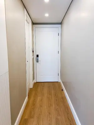 an empty hallway with a white door and wooden floors at Bolahenk Suites in Istanbul
