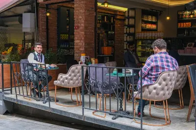 two men sitting at a table in front of a store at Hotel Martin in Istanbul