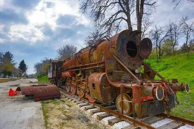 an old rusty train sitting on the tracks at İstasyon Otel in Boyalık