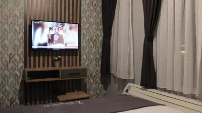 a bedroom with a tv and a bed and curtains at İstasyon Otel in Boyalık