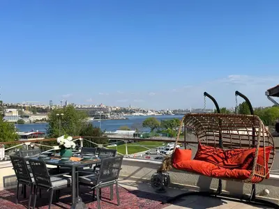 a wicker chair sitting on a patio with a table at Waterfront Apartment by the Tram- Terrace with Dome & Golden Horn View in Fatih in Istanbul