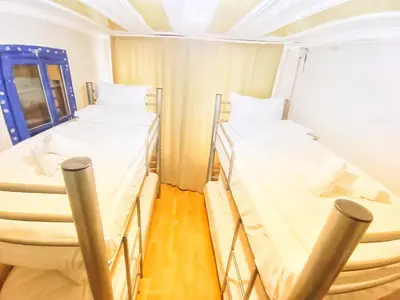 two beds in a small room with a window at Taksim History Wooden Hostel in Istanbul